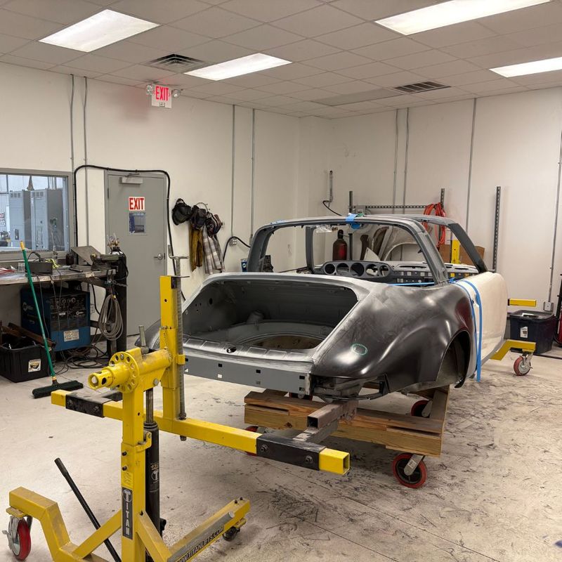 A vintage car shell sits on a professional restoration rotisserie as we prepare the chassis for a comprehensive rebuild. A vintage car shell sits on a professional restoration rotisserie as we prepare the chassis for a comprehensive rebuild.